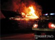 Пожарный автомобиль на фоне горящего дома