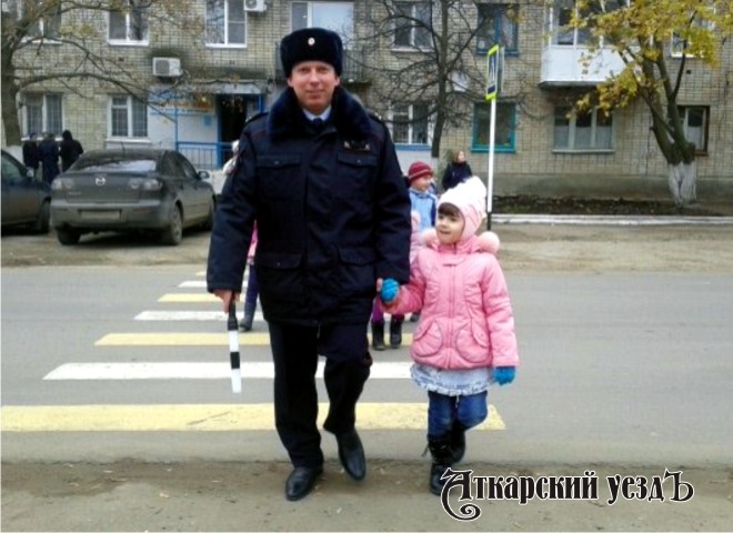Инспектор по пропаганде БДД отделения ГИБДД по Аткарскому району Алексей Левин переводит детей через дорогу
