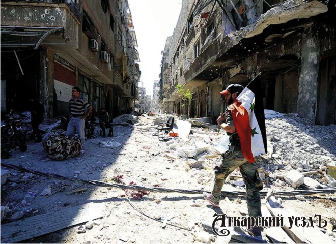 Мужчина с сирийским флагом на фоне последствий бомбардировок