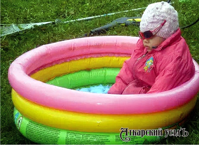 Девочка в куртке сидит в бассейне