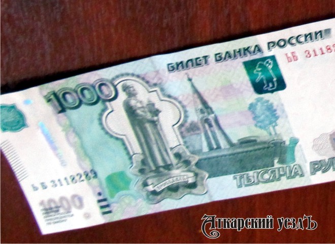 Купюра номиналом 1000 рублей, лежащая на столе