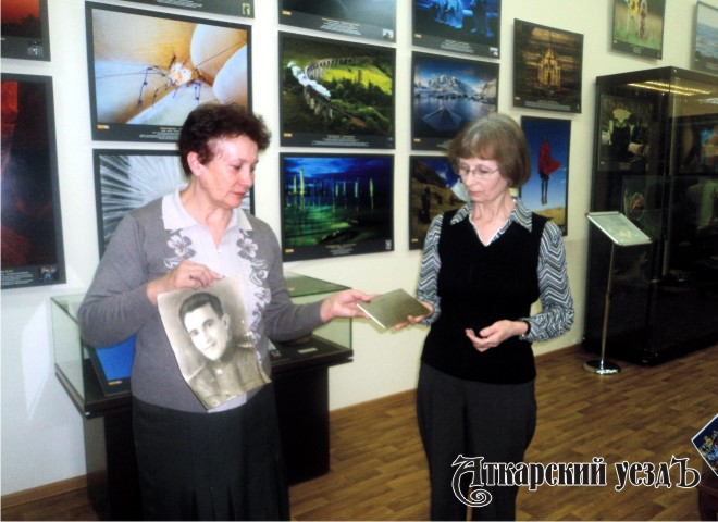 Сотрудница музея передает табличку Лидии Ефимовой