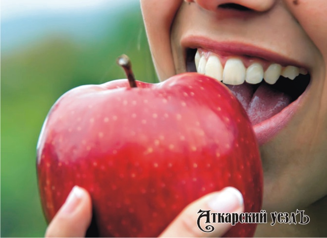 Женщина с красивыми зубами кушает яблоко